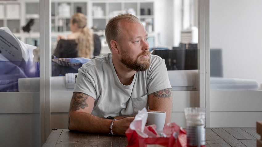 En man sitter själv vid ett bord, inomhus