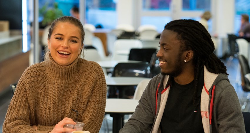 Man och kvinna sitter vid ett runt bord på cafe