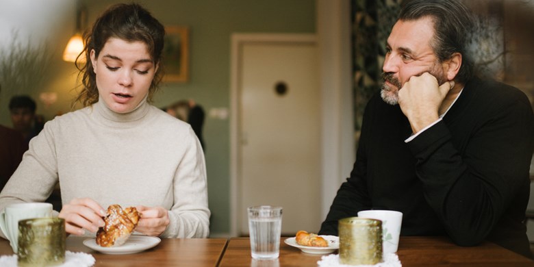 En man och en kvinna sitter vid ett bord, framför dem står kaffekoppar och varsin bulle